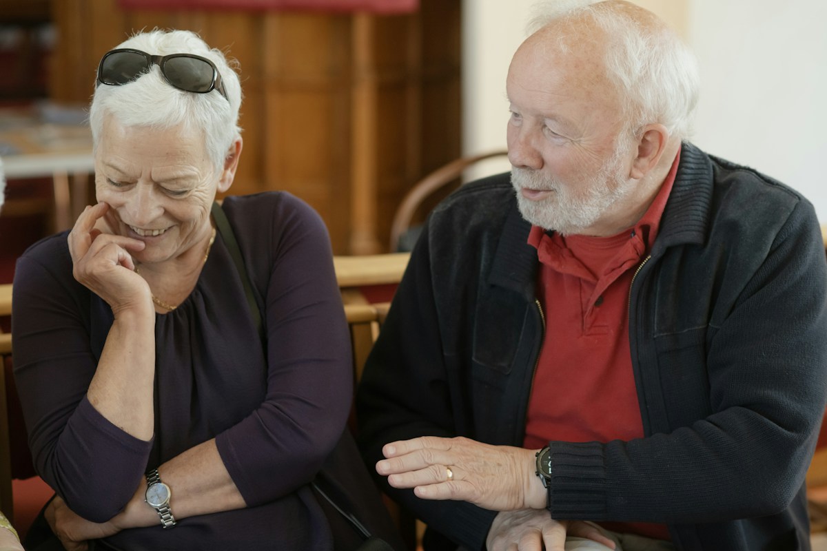 Two older adults sharing a relaxed laugh at a table
